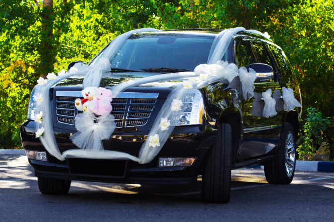 decorated car with wedding ribbons on city street escalade